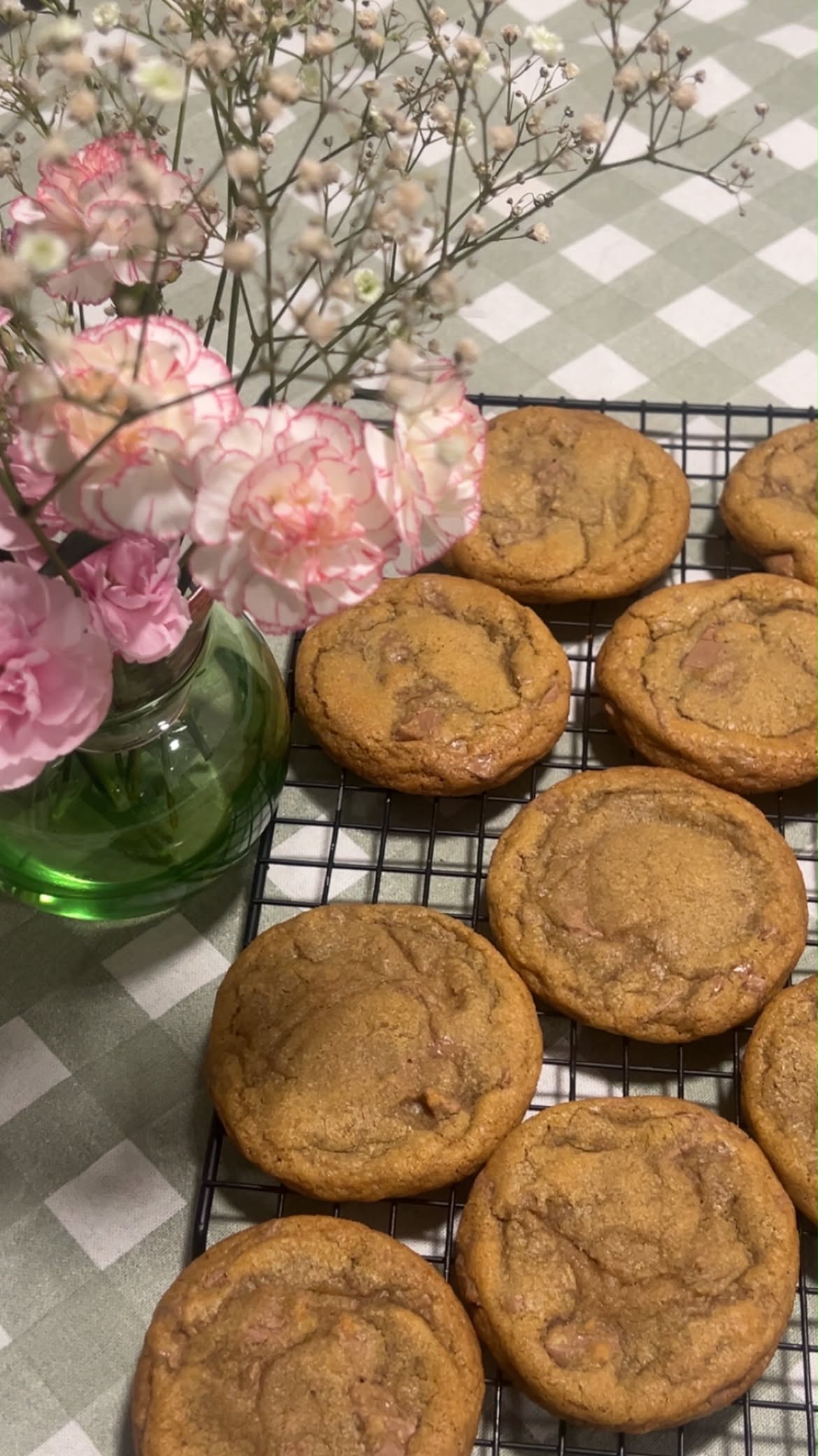 Brown butter chocolate chunk cookies beside a vase of pink flowers